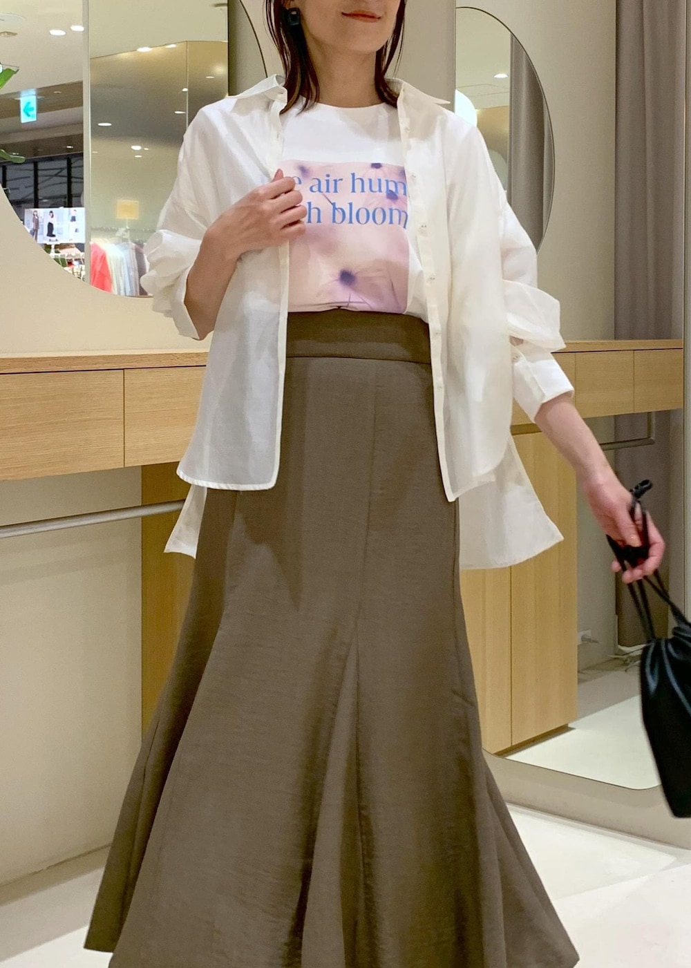 グリーン系のスカート、ホワイト系のシャツ/ブラウス、ブラック系のハンドバッグを着用したレディースの春コーディネートの7枚目の写真