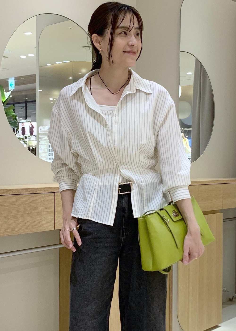 ホワイト系のキャミソール、ベージュ系のパンプス、ブラック系のデニムパンツを着用したレディースの春コーディネートの5枚目の写真