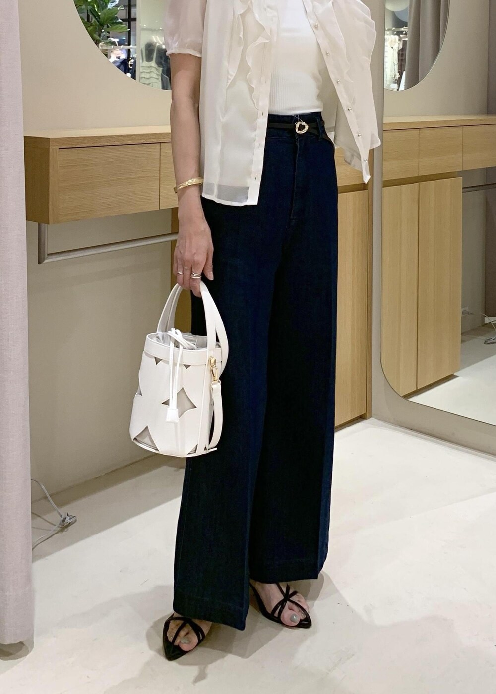 ホワイト系のキャミソール、ブラック系のサンダル、ブルー系のデニムパンツを着用したレディースの夏コーディネートの10枚目の写真