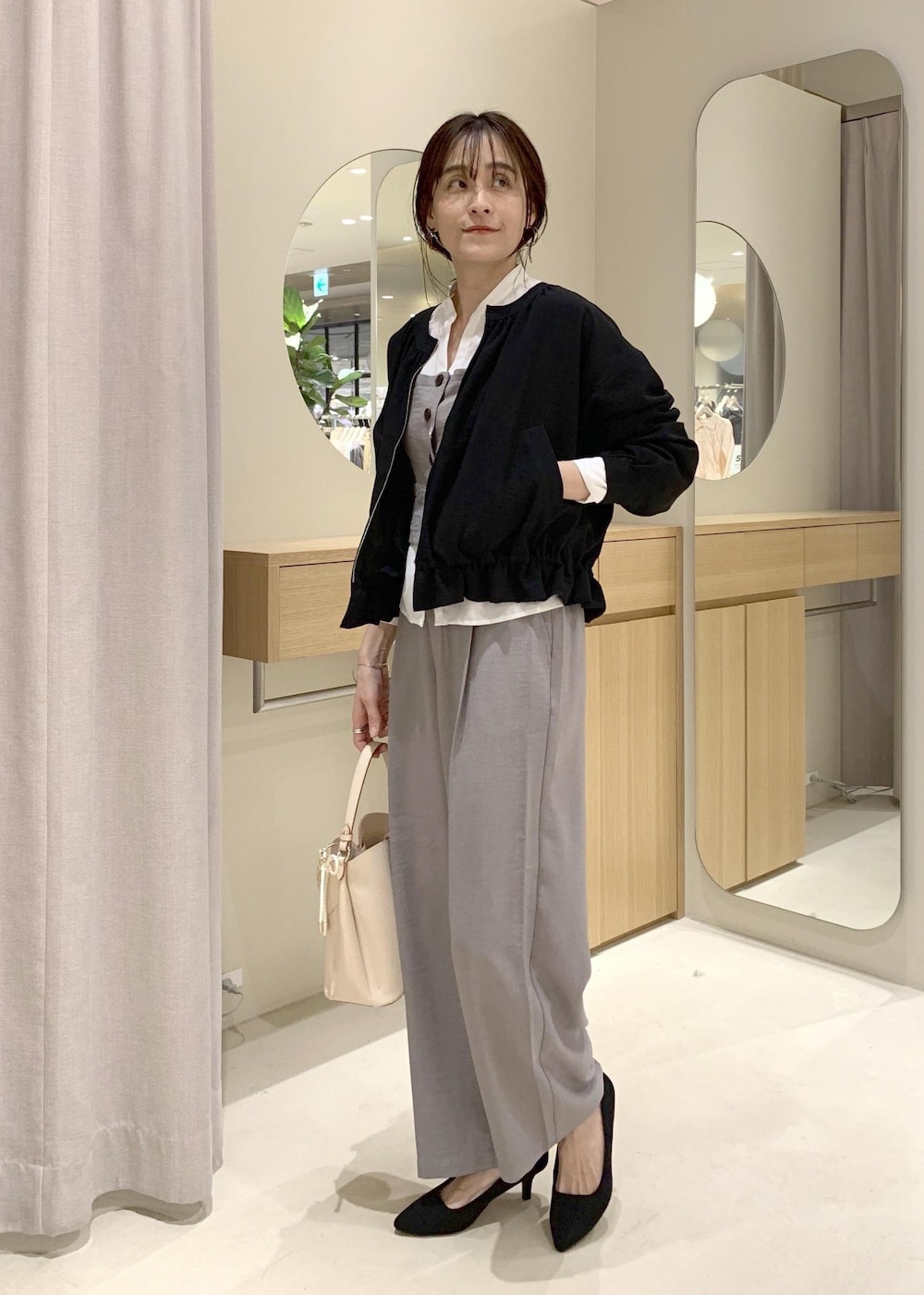 ベージュ系のショルダーバッグ、ブラック系のブルゾン、グレー系のシャツ/ブラウスを着用したレディースの春コーディネートの3枚目の写真