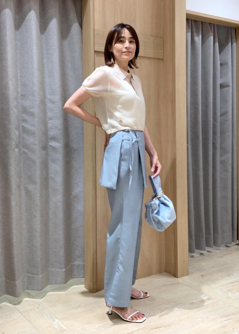 ホワイト系のサンダル、ブルー系のスラックス、ブルー系のハンドバッグを着用したレディースの夏コーディネートの3枚目の写真