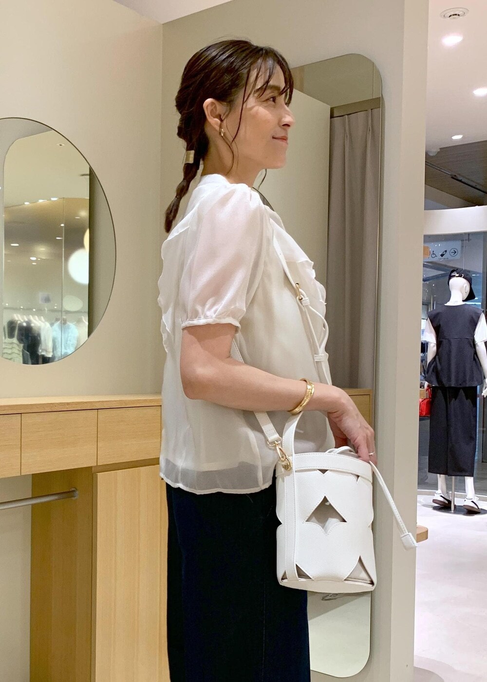 ホワイト系のキャミソール、ブラック系のサンダル、ブルー系のデニムパンツを着用したレディースの夏コーディネートの6枚目の写真