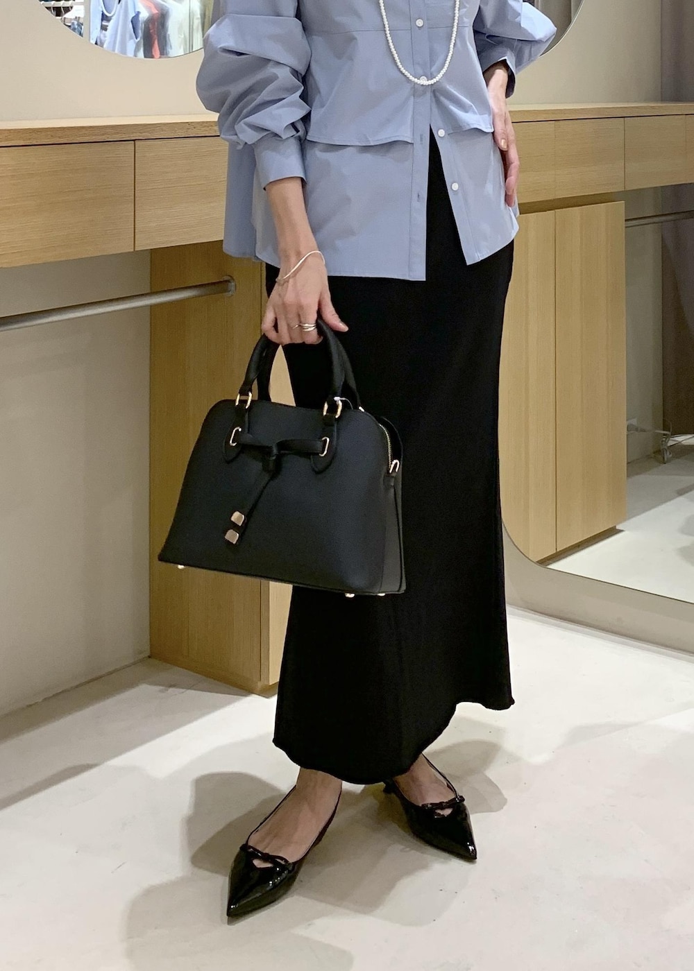 ブラック系のパンプス、ブラック系のスカート、ブルー系のシャツ/ブラウスを着用したレディースの夏コーディネートの9枚目の写真