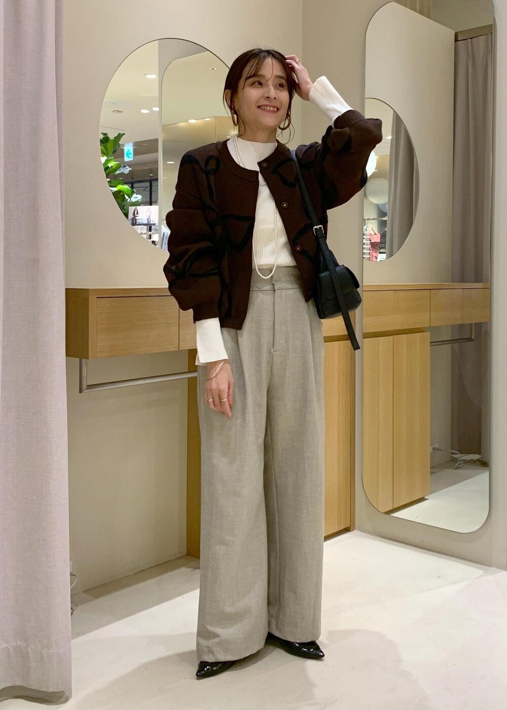 ブラック系のショルダーバッグ、ベージュ系のその他パンツ、ブラウン系のカーディガン/ボレロを着用したレディースの秋コーディネートの3枚目の写真