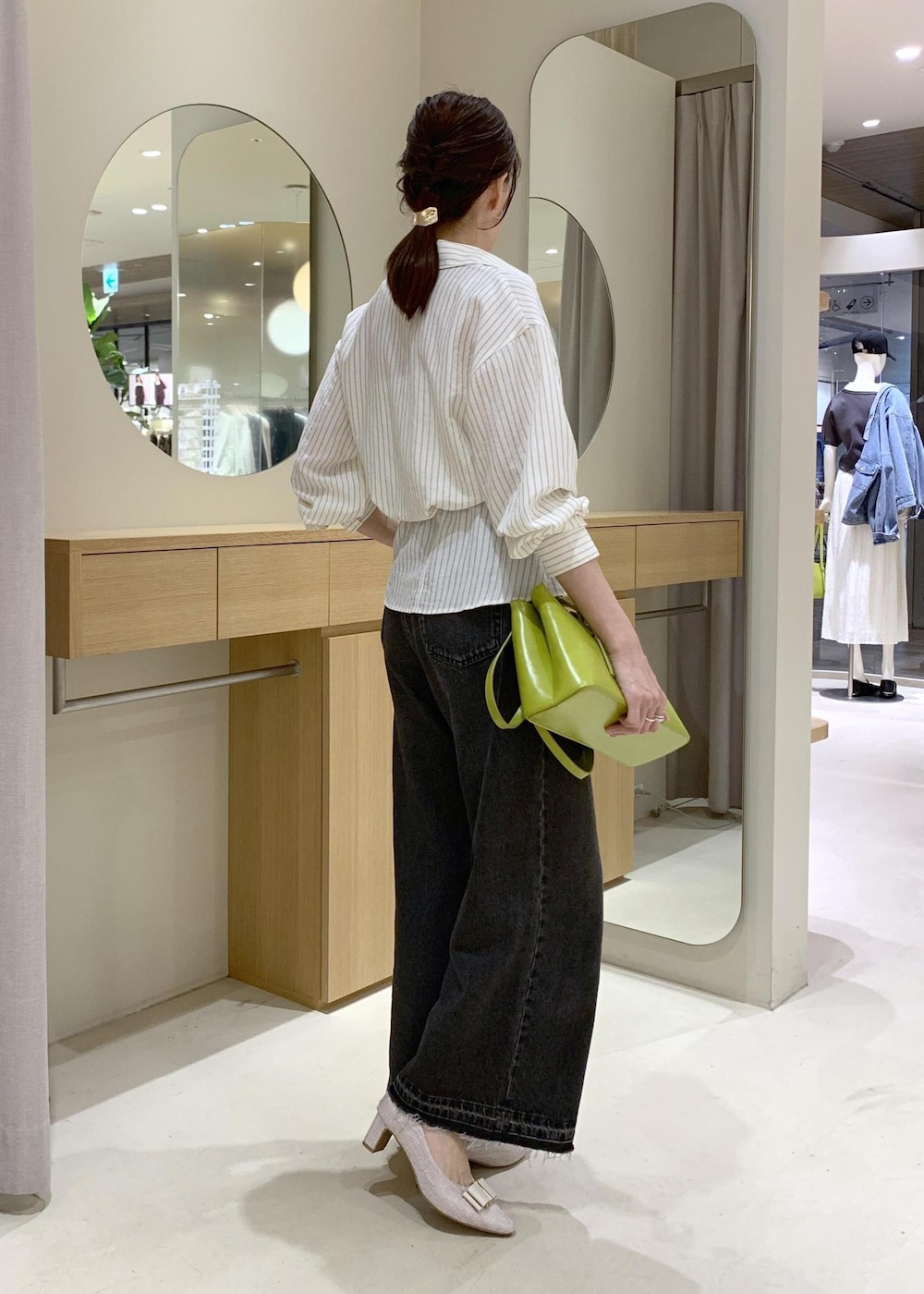 ホワイト系のキャミソール、ベージュ系のパンプス、ブラック系のデニムパンツを着用したレディースの春コーディネートの3枚目の写真