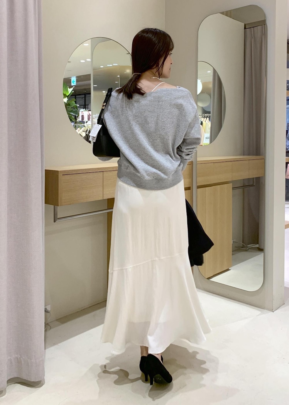 ブラック系のショルダーバッグ、ブルー系のナイロンジャケット、ホワイト系のキャミソールを着用したレディースの春コーディネートの8枚目の写真