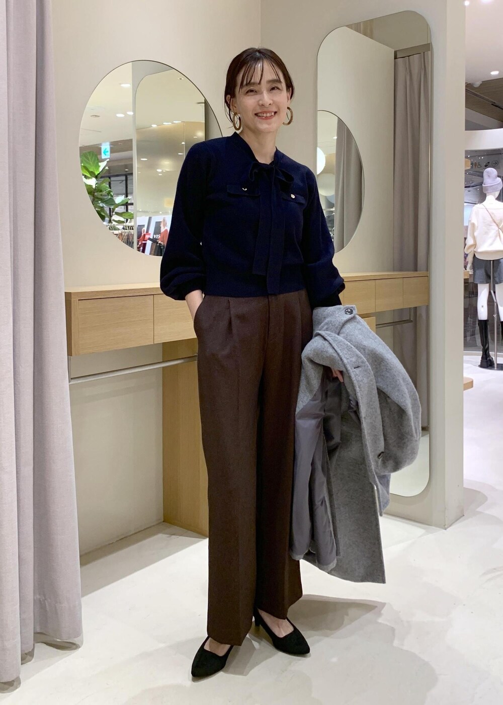 ブルー系のハンドバッグ、ブラウン系のスラックス、グレー系のその他アウターを着用したレディースの冬コーディネートの5枚目の写真