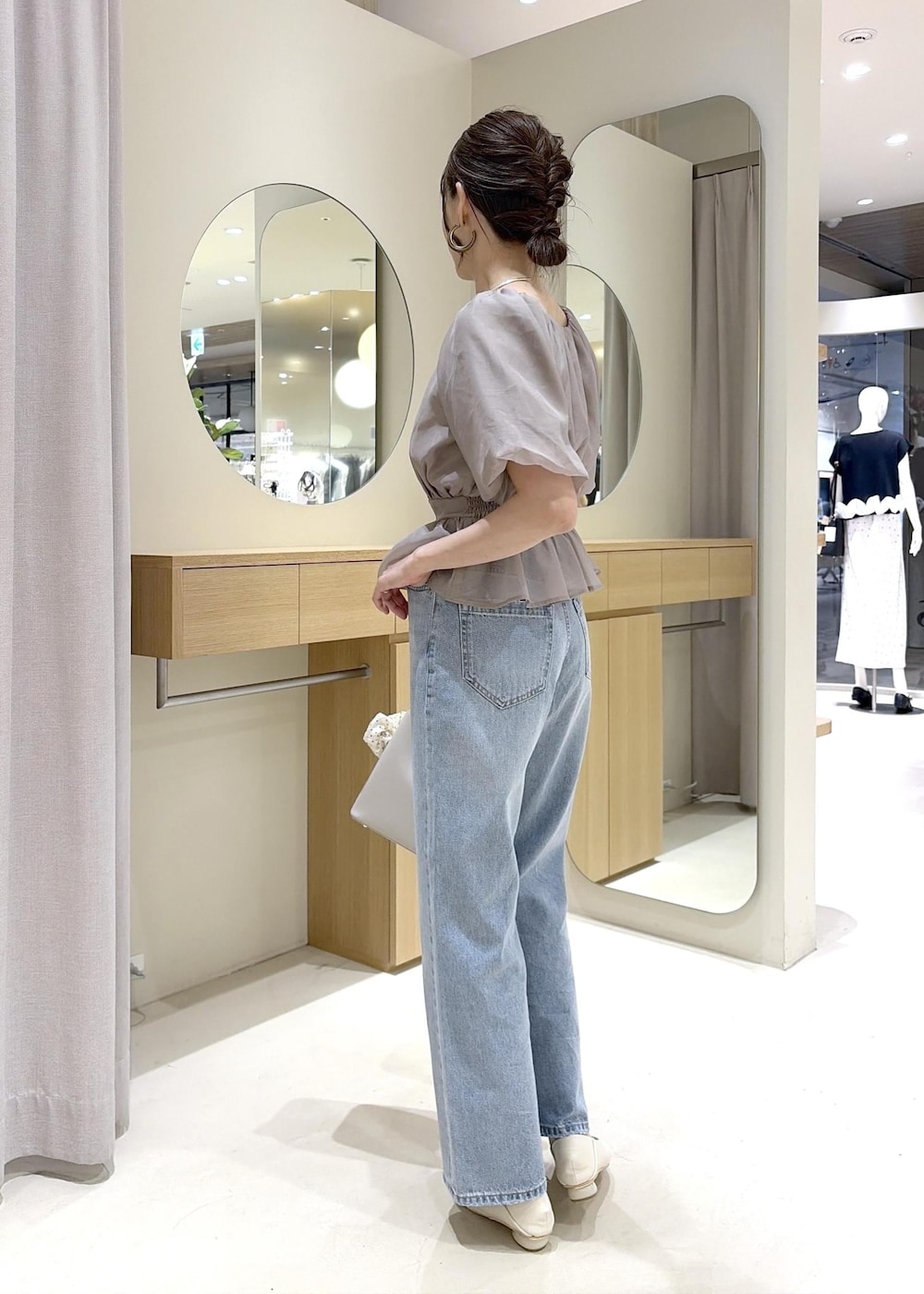 ホワイト系のパンプス、ベージュ系のシャツ/ブラウス、ブルー系のデニムパンツを着用したレディースの夏コーディネートの3枚目の写真