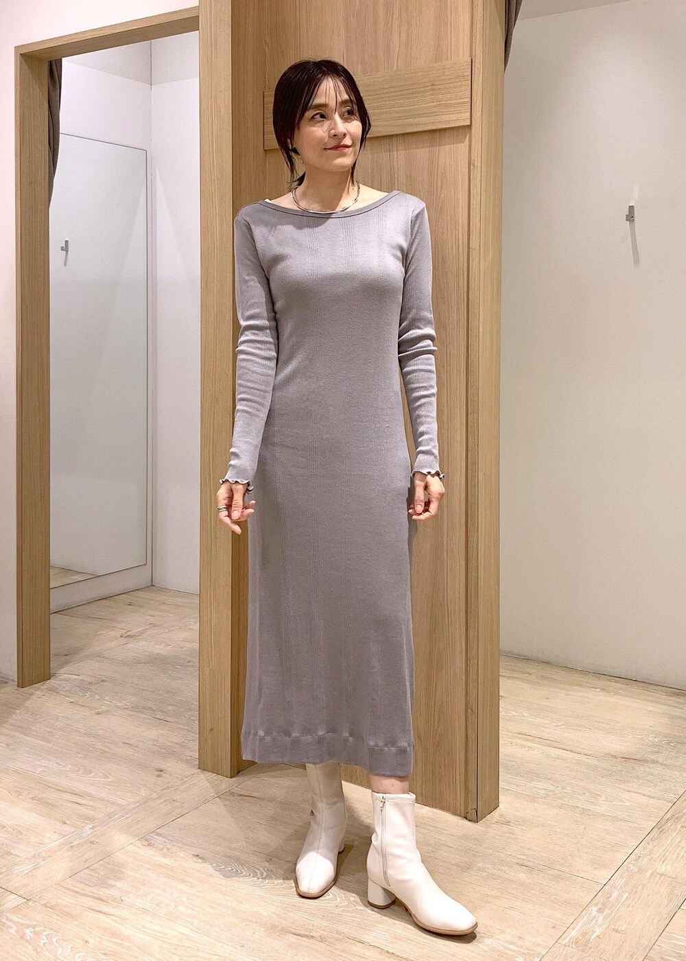 シルバー系のショルダーバッグ、ホワイト系のブーツ、グレー系のワンピースを着用したレディースの冬コーディネートの4枚目の写真