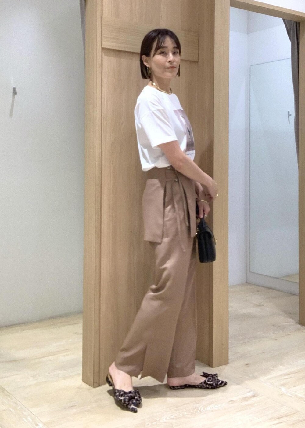 ホワイト系のTシャツ/カットソー、その他のサンダル、ブラウン系のスラックスを着用したレディースの夏コーディネートの4枚目の写真