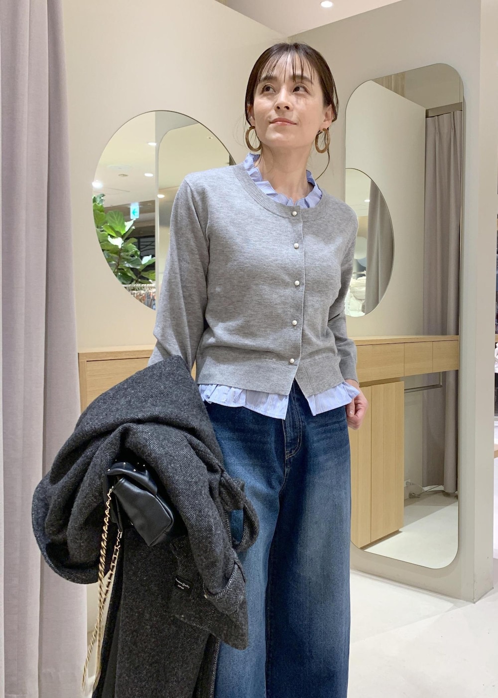 ブルー系のデニムパンツ、グレー系のその他アウター、ブラック系のショルダーバッグを着用したレディースの冬コーディネートの5枚目の写真