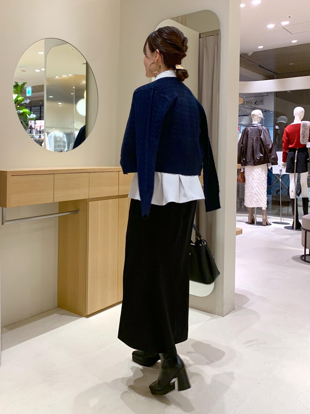 ブラック系のショルダーバッグ、ブラック系のスカート、ブルー系のカーディガン/ボレロを着用したレディースの秋コーディネートの3枚目の写真