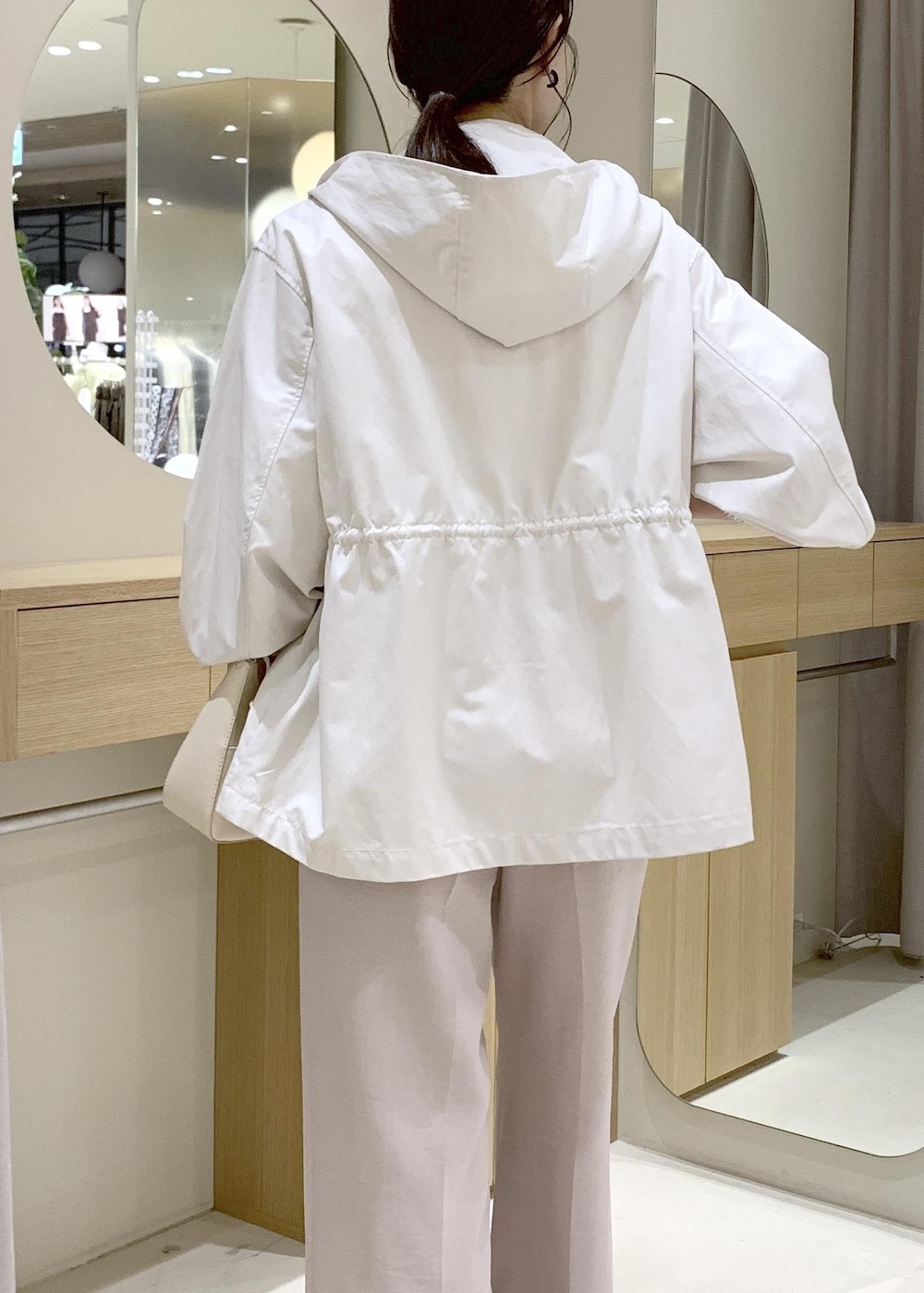 ホワイト系のショルダーバッグ、ベージュ系のパンプス、ホワイト系のナイロンジャケットを着用したレディースの春コーディネートの10枚目の写真