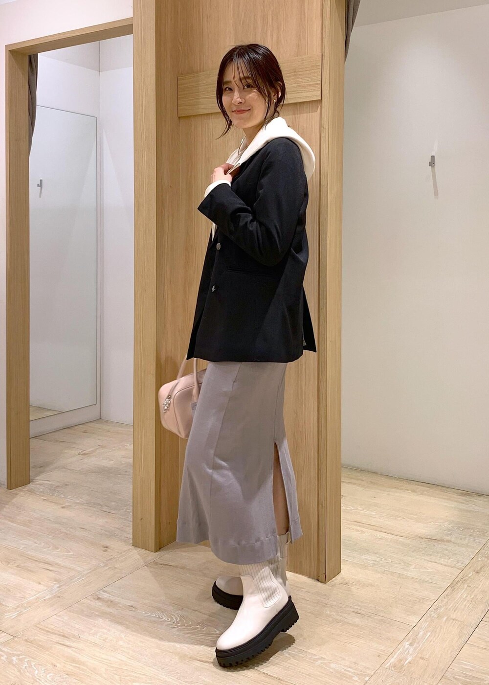 ホワイト系のブーツ、ホワイト系のパーカー、ブラック系のテーラードジャケットを着用したレディースの冬コーディネートの3枚目の写真