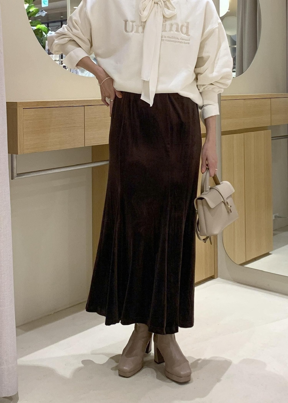 ベージュ系のショルダーバッグ、ブラウン系のスカート、ベージュ系のブーツを着用したレディースの秋コーディネートの8枚目の写真