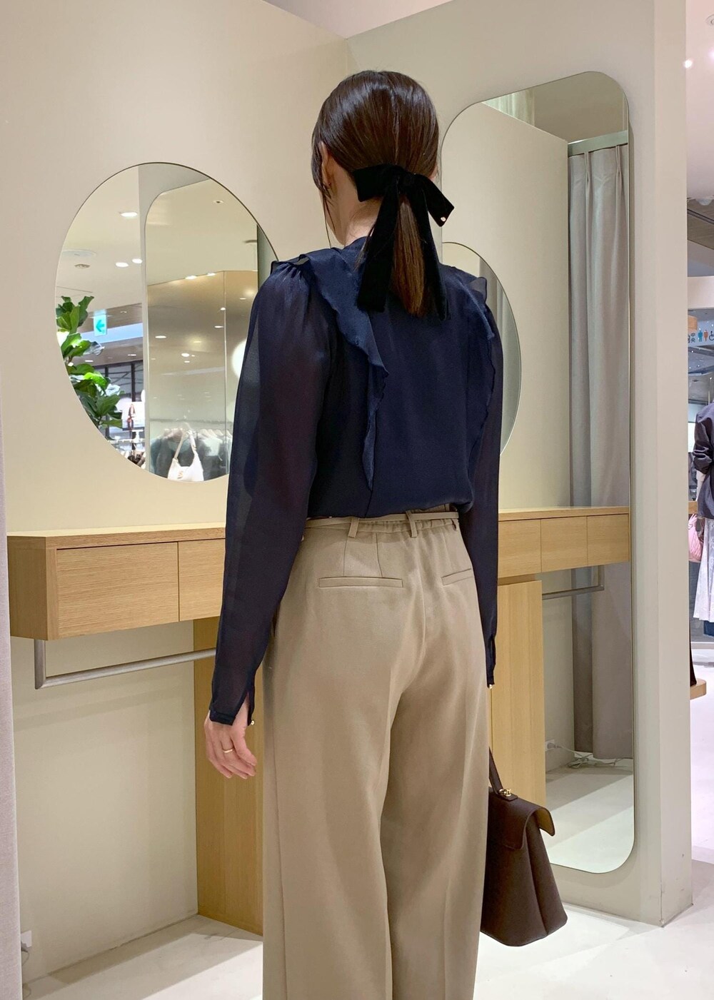 ブラウン系のハンドバッグ、ホワイト系のパンプス、ブルー系のシャツ/ブラウスを着用したレディースの秋コーディネートの7枚目の写真