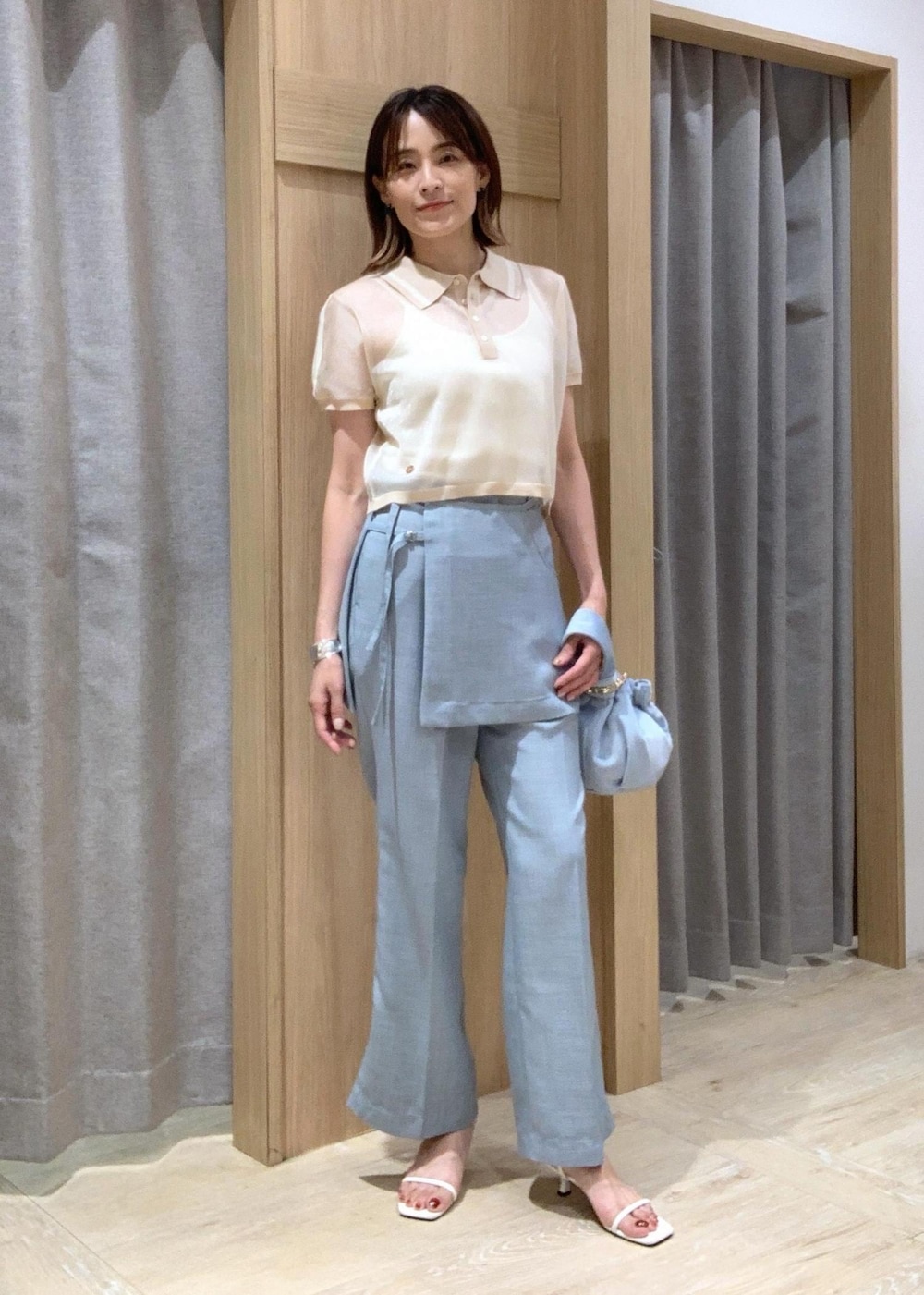 ホワイト系のサンダル、ブルー系のスラックス、ブルー系のハンドバッグを着用したレディースの夏コーディネートの2枚目の写真