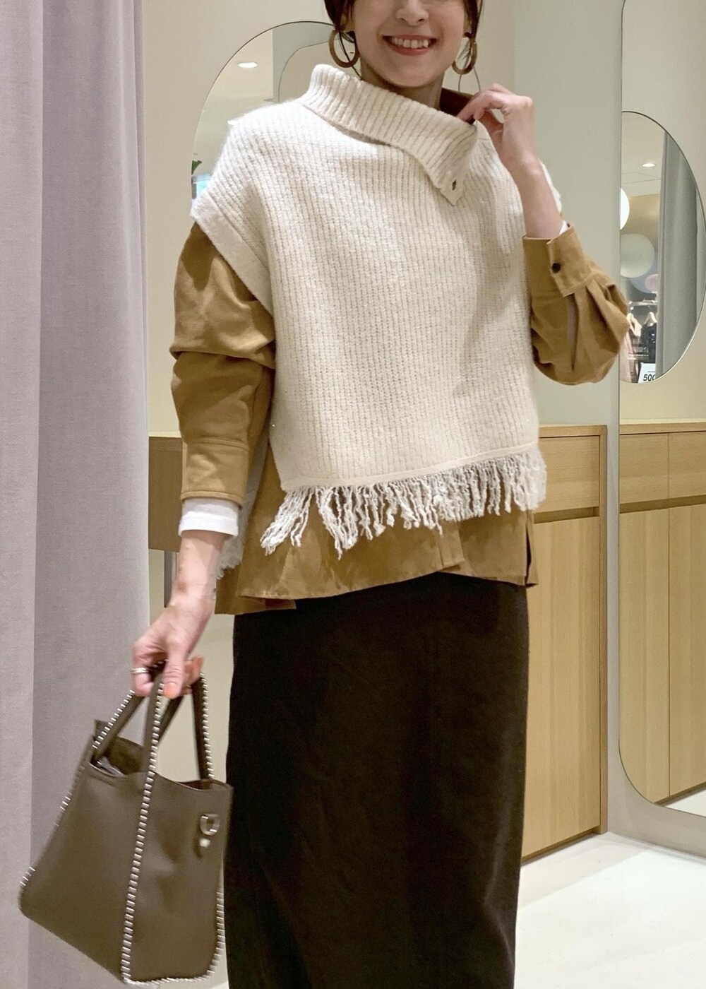 ベージュ系のブーツ、ブラウン系のスカート、イエロー系のシャツ/ブラウスを着用したレディースの秋コーディネートの5枚目の写真