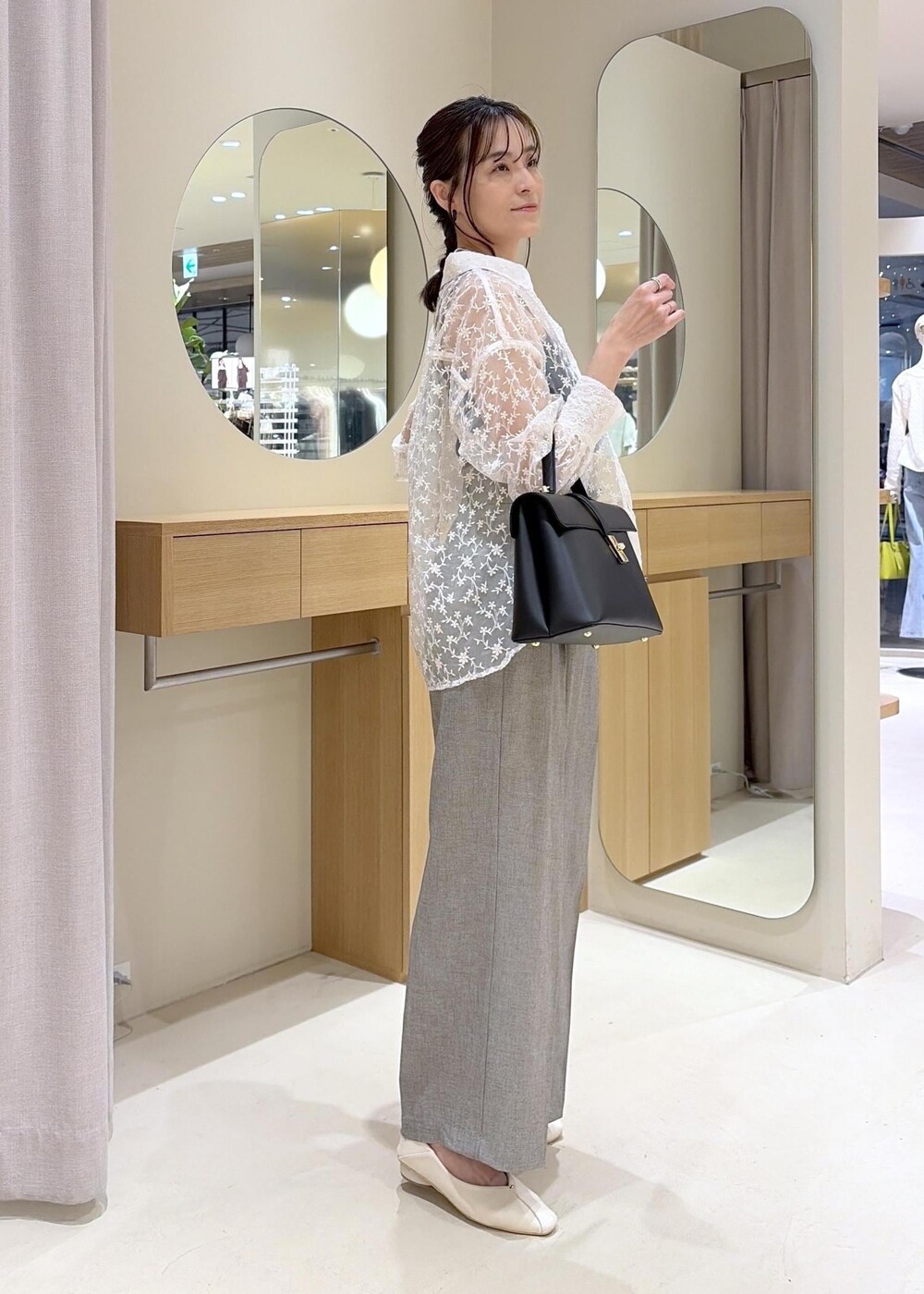 ブラック系のハンドバッグ、ホワイト系のパンプス、グレー系のその他パンツを着用したレディースの春コーディネートの3枚目の写真