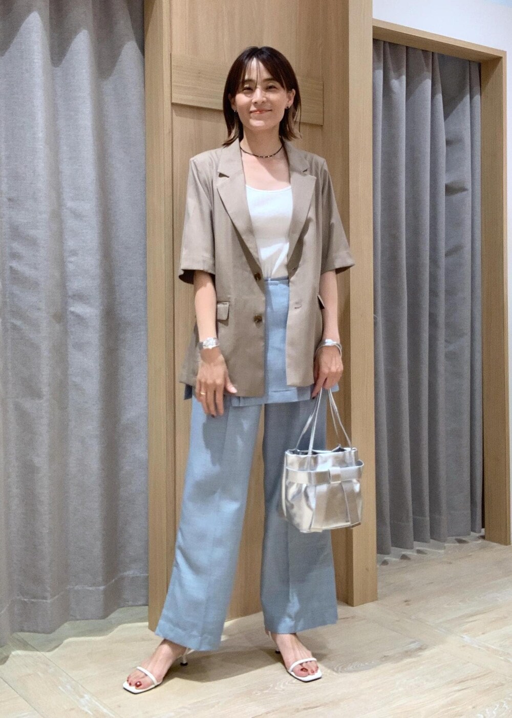 ホワイト系のキャミソール、ホワイト系のサンダル、ブルー系のスラックスを着用したレディースの夏コーディネートの2枚目の写真