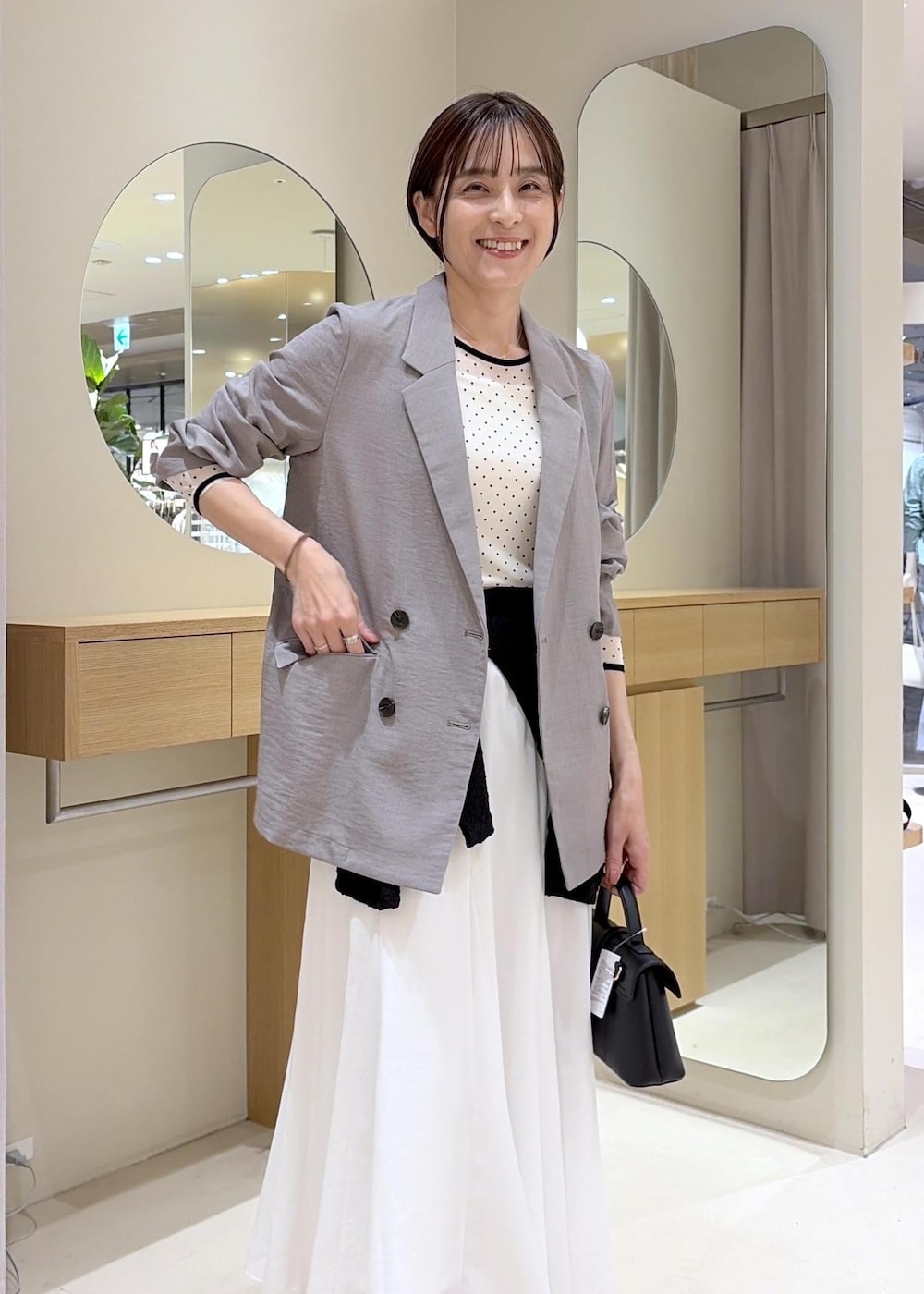 ブラウン系のパンプス、ホワイト系のスカート、ブラック系のカーディガン/ボレロを着用したレディースの春コーディネートの5枚目の写真