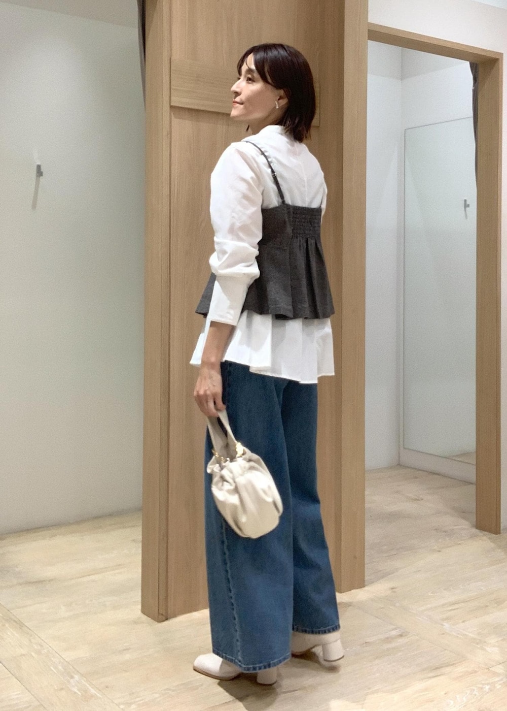 ホワイト系のハンドバッグ、ブルー系のデニムパンツ、ホワイト系のブーツを着用したレディースの秋コーディネートの5枚目の写真