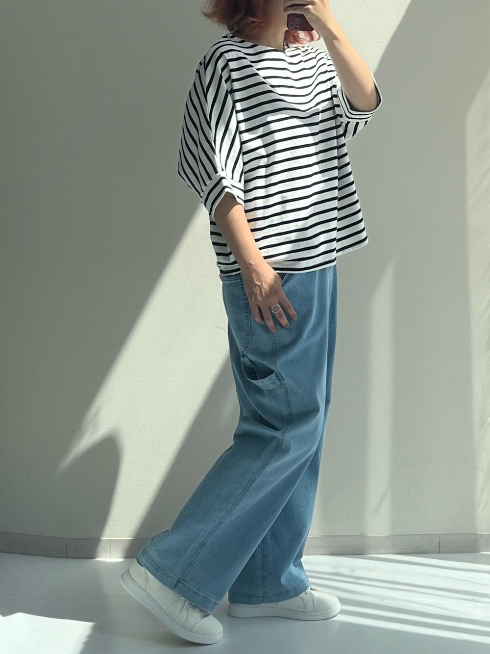 ブルー系のパンツ、シルバー系のTシャツ/カットソー、ホワイト系のスニーカーを着用したレディースの秋コーディネートの2枚目の写真