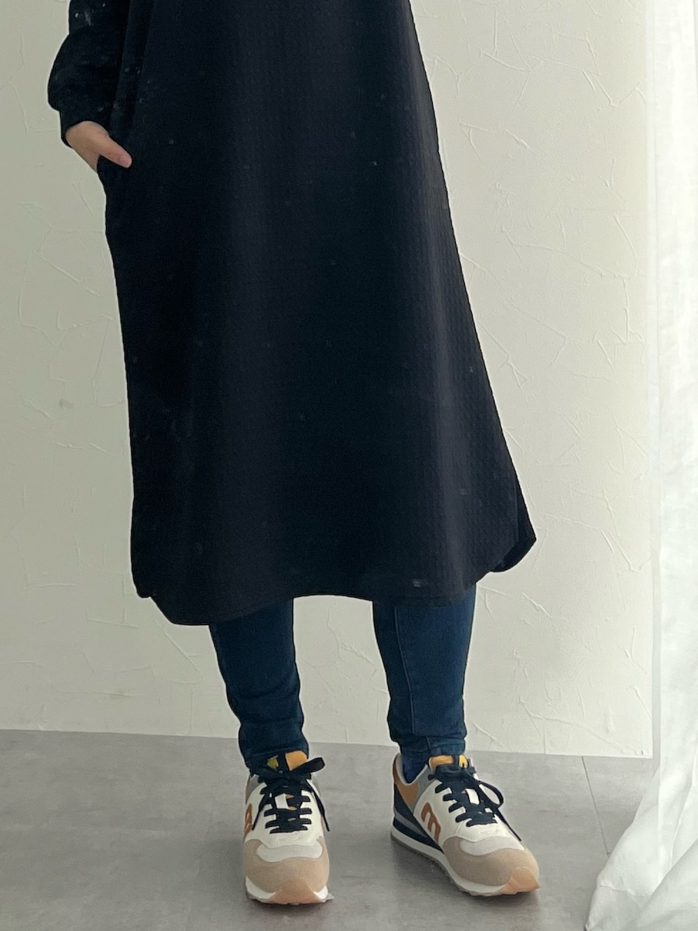 ブルー系のパンツ、ブラック系のスニーカー、ブラック系のワンピースを着用したレディースの秋コーディネートの4枚目の写真