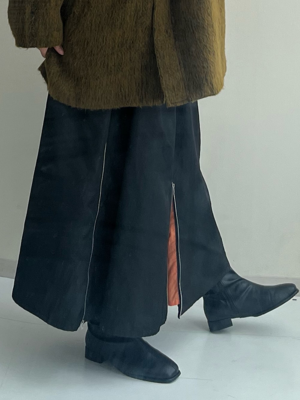 ブラック系のブーツ、ブラック系のスカート、イエロー系のジャケット/アウターを着用したレディースの秋コーディネートの3枚目の写真