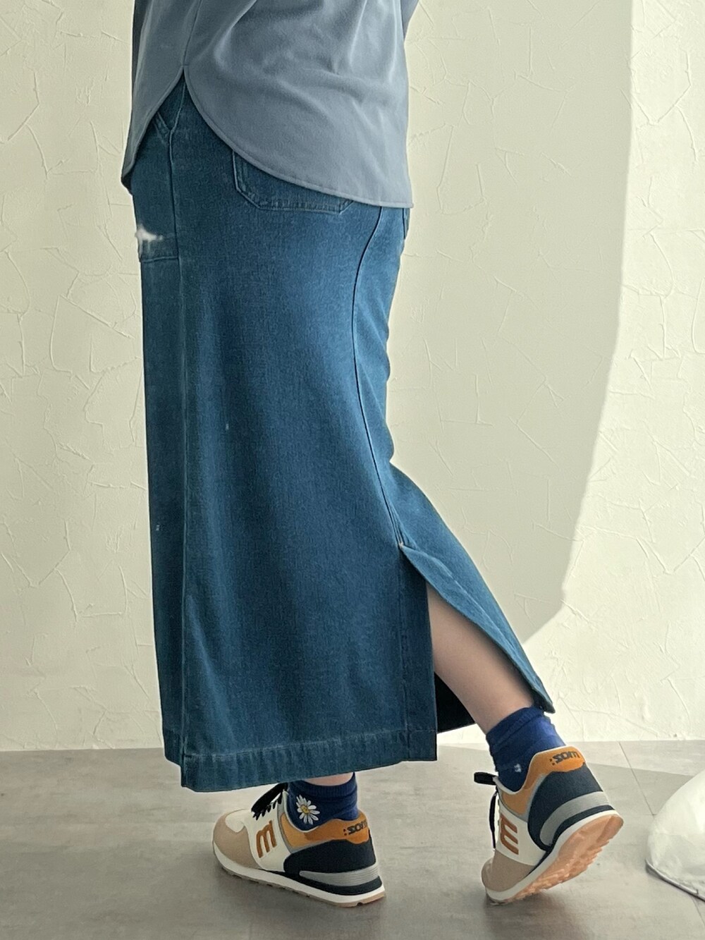 ブラック系のスニーカー、ブルー系のスカート、ホワイト系のTシャツ/カットソーを着用したレディースの秋コーディネートの3枚目の写真