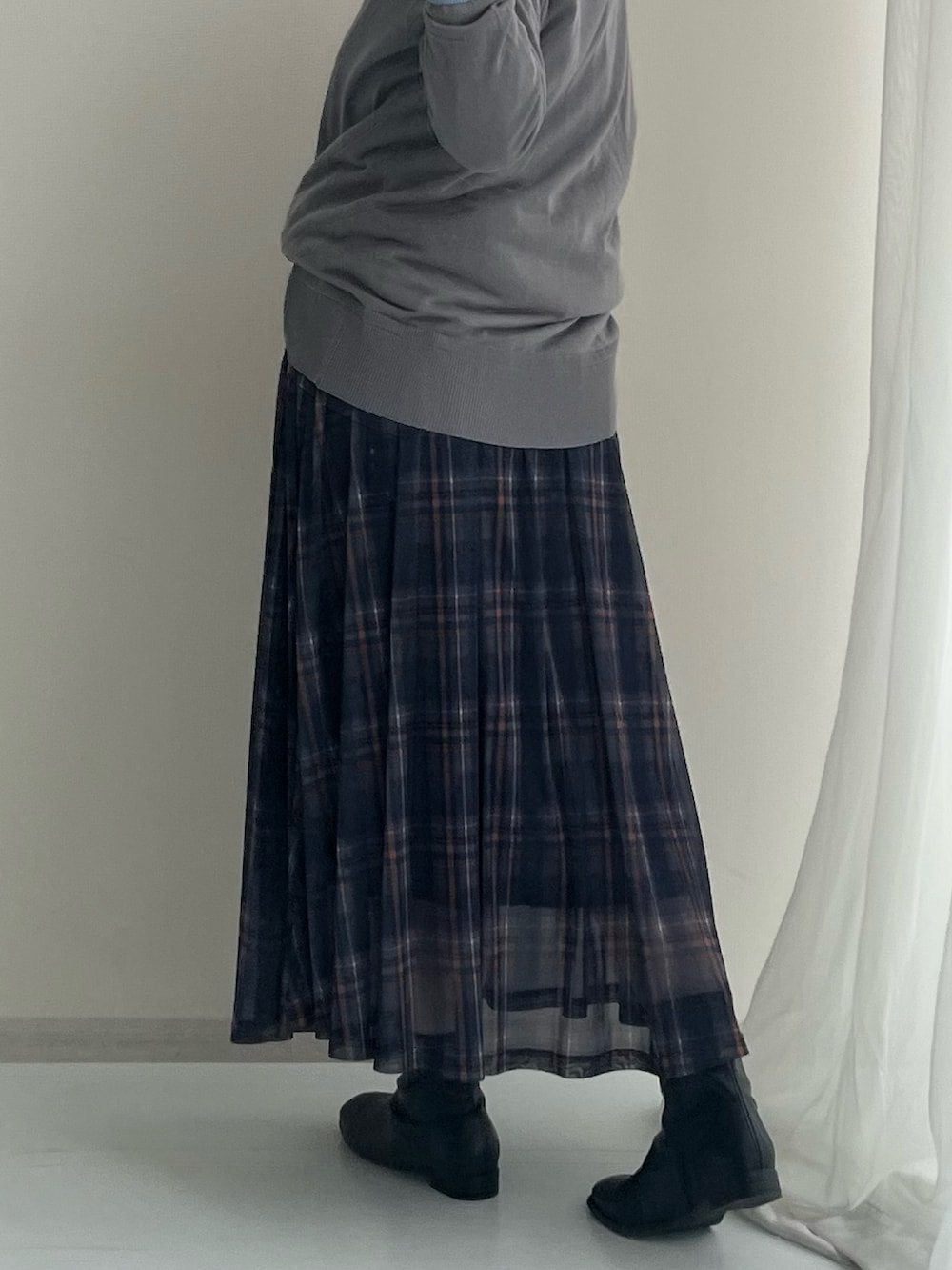 ブルー系のスカート、グレー系のカーディガン/ボレロ、ブラック系のブーツを着用したレディースの春コーディネートの5枚目の写真