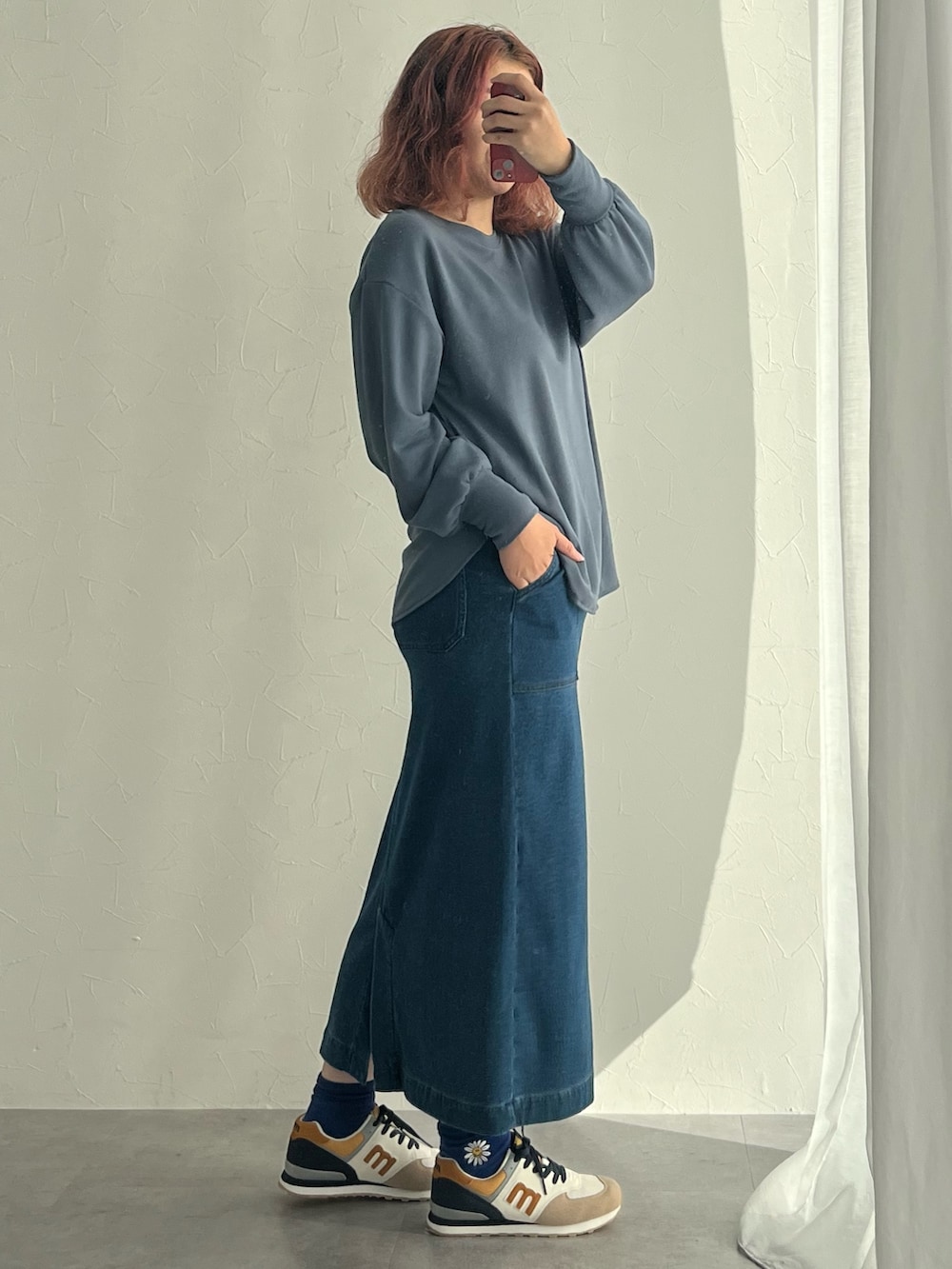 ブラック系のスニーカー、ブルー系のスカート、ホワイト系のTシャツ/カットソーを着用したレディースの秋コーディネートの2枚目の写真