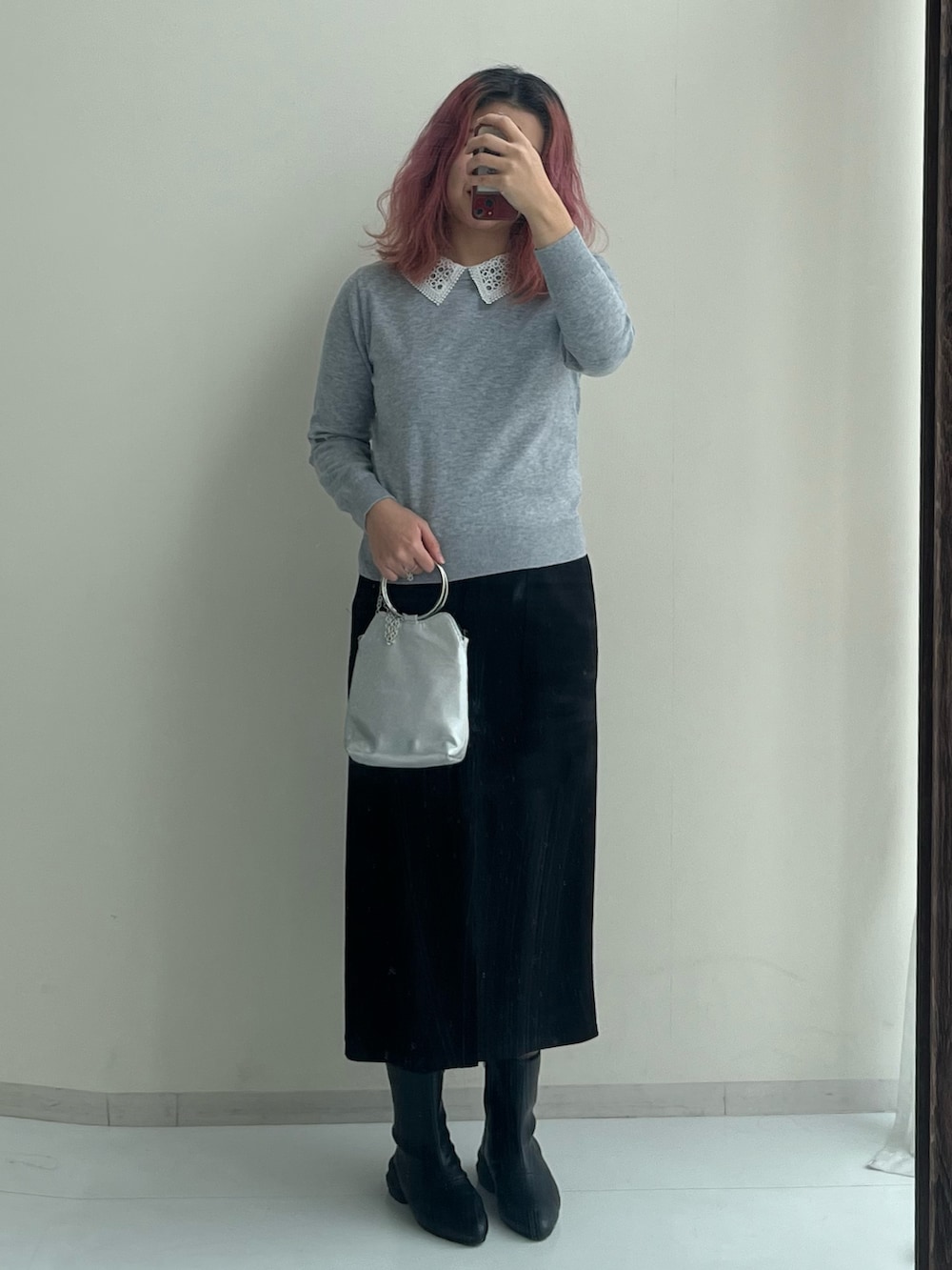ブラック系のスカート、ブラック系のブーツ、グレー系のニット/セーターを着用したレディースの冬コーディネートの2枚目の写真