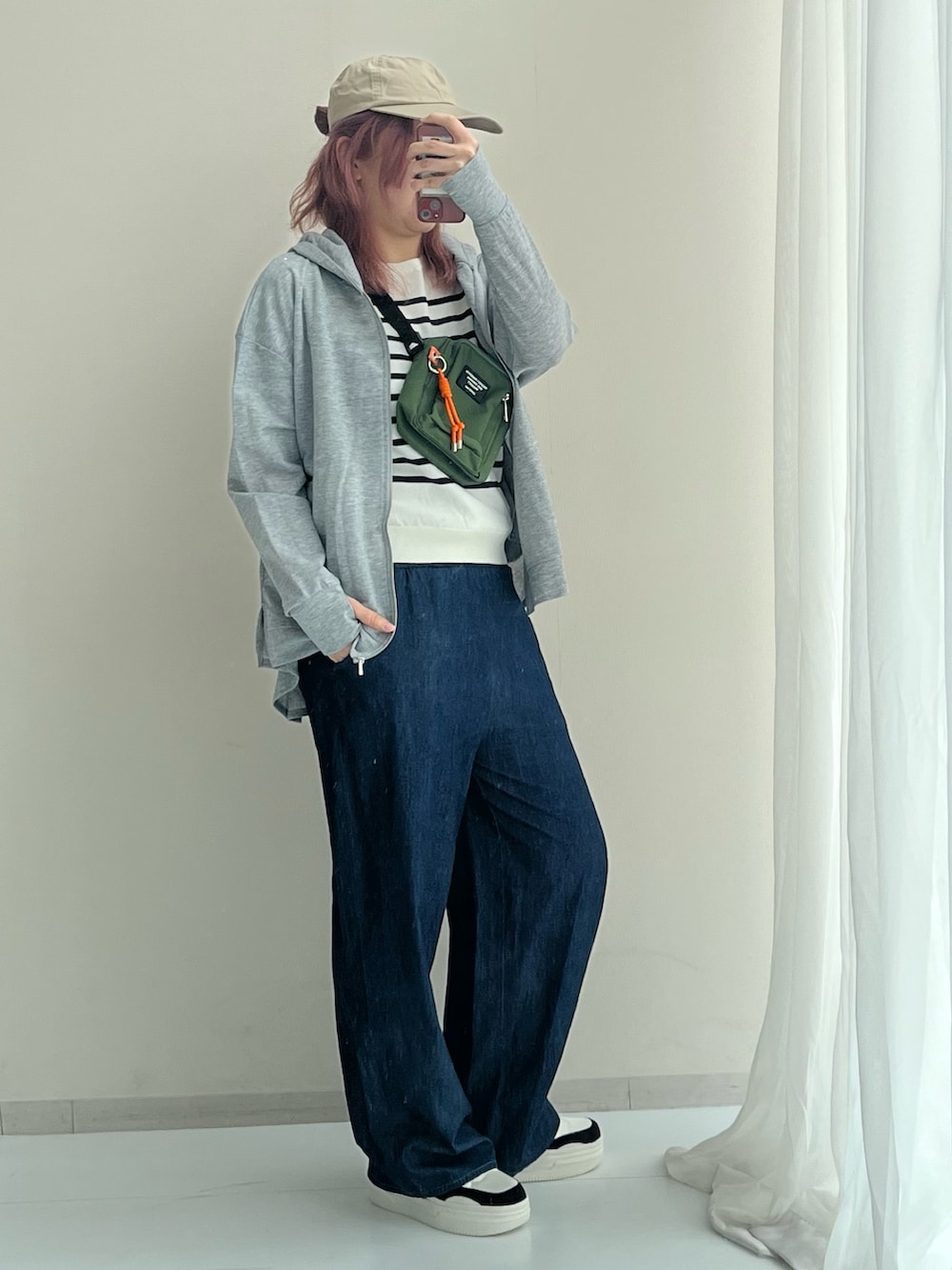 グレー系のセットアップ、ホワイト系のニット/セーター、ブラック系のスニーカーを着用したレディースの春コーディネートの2枚目の写真