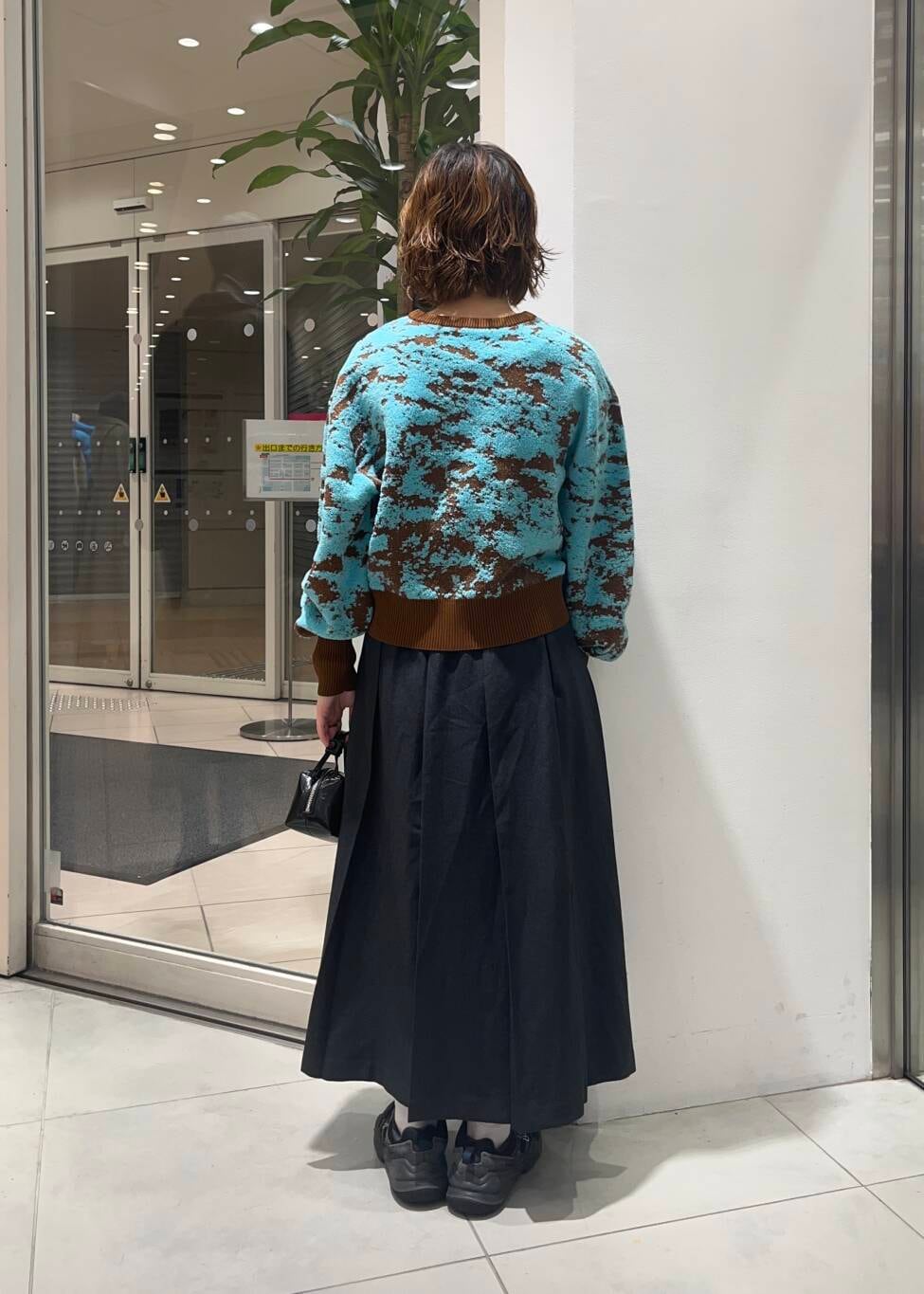 ブラウン系のニット/セーター、グレー系のワンピース、ブラック系のハンドバッグを着用したレディースの秋コーディネートの3枚目の写真