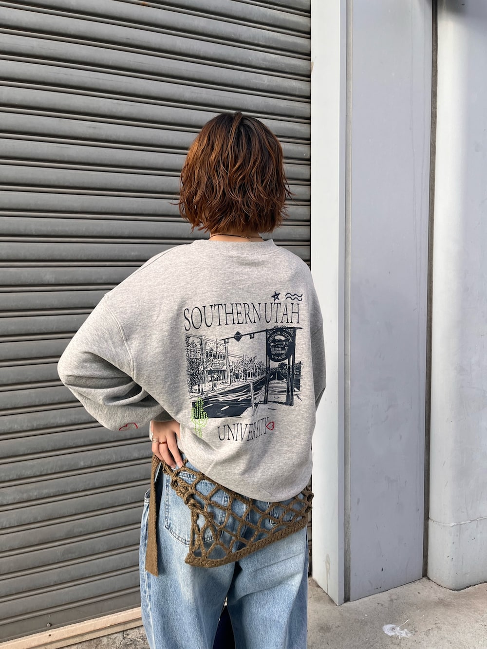 ブルー系のデニムパンツ、ブルー系のショルダーバッグ、グレー系のスウェットを着用したレディースの秋コーディネートの2枚目の写真