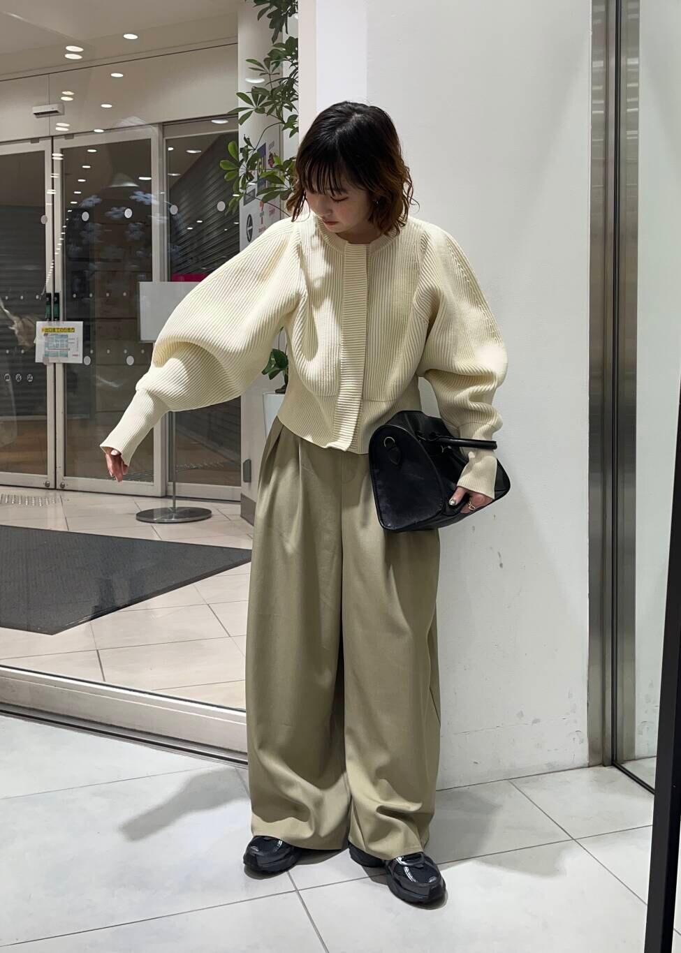 ブラック系のボストンバッグ、ベージュ系のその他パンツ、ホワイト系のカーディガン/ボレロを着用したレディースの冬コーディネートの2枚目の写真