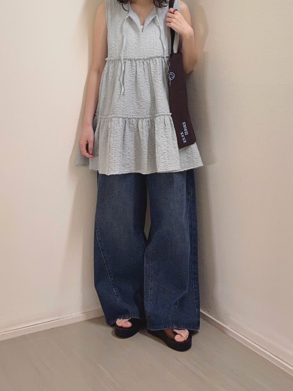 ブルー系のチュニック、ブルー系のデニムパンツ、ブラウン系のサンダルを着用したレディースの春コーディネートの4枚目の写真