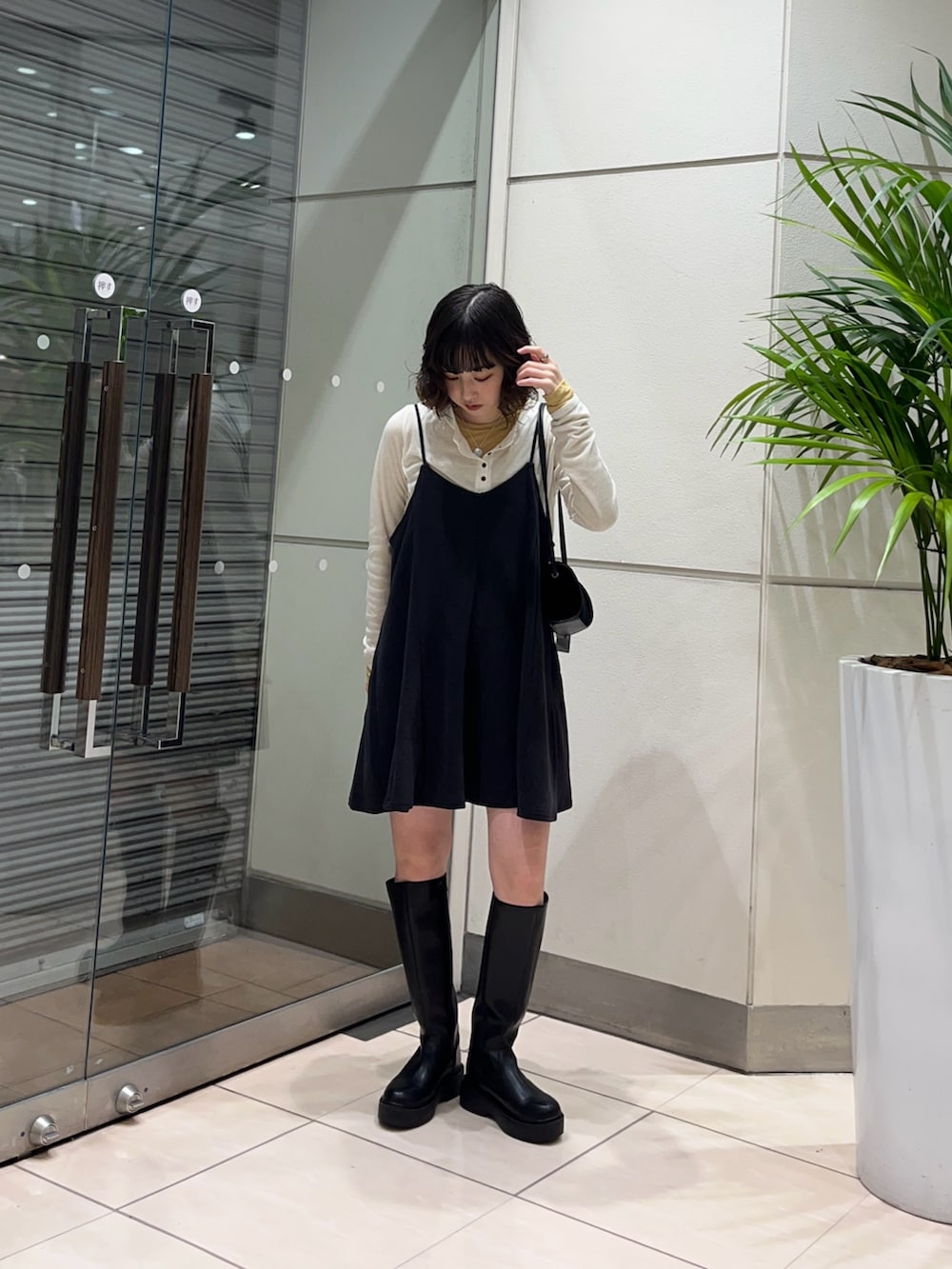 ブラック系のブーツ、グレー系のワンピース、ブラック系のショルダーバッグを着用したレディースの秋コーディネートの2枚目の写真