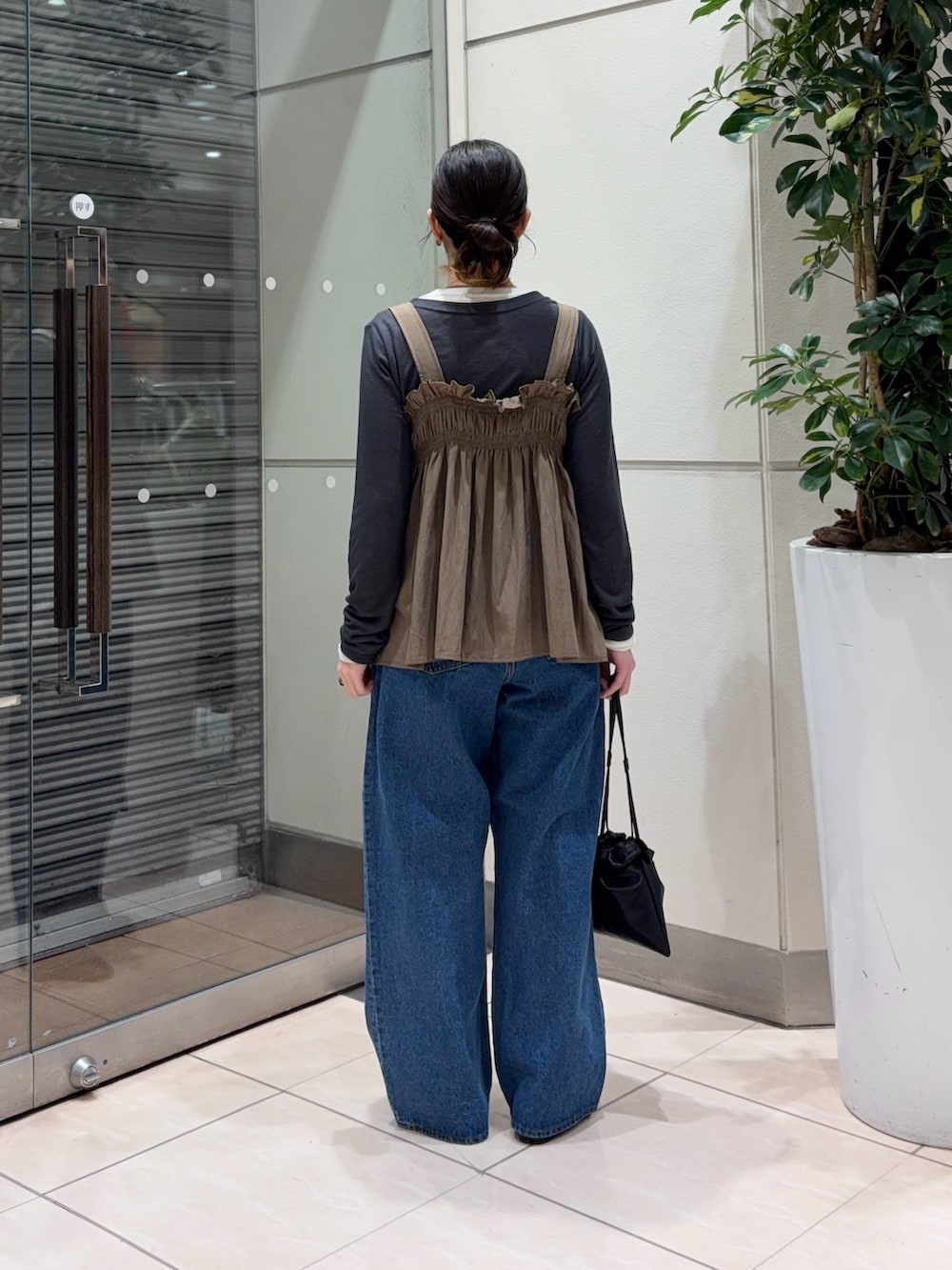 ブルー系のデニムパンツ、ブラック系のその他シューズ、ブラック系のショルダーバッグを着用したレディースの春コーディネートの4枚目の写真