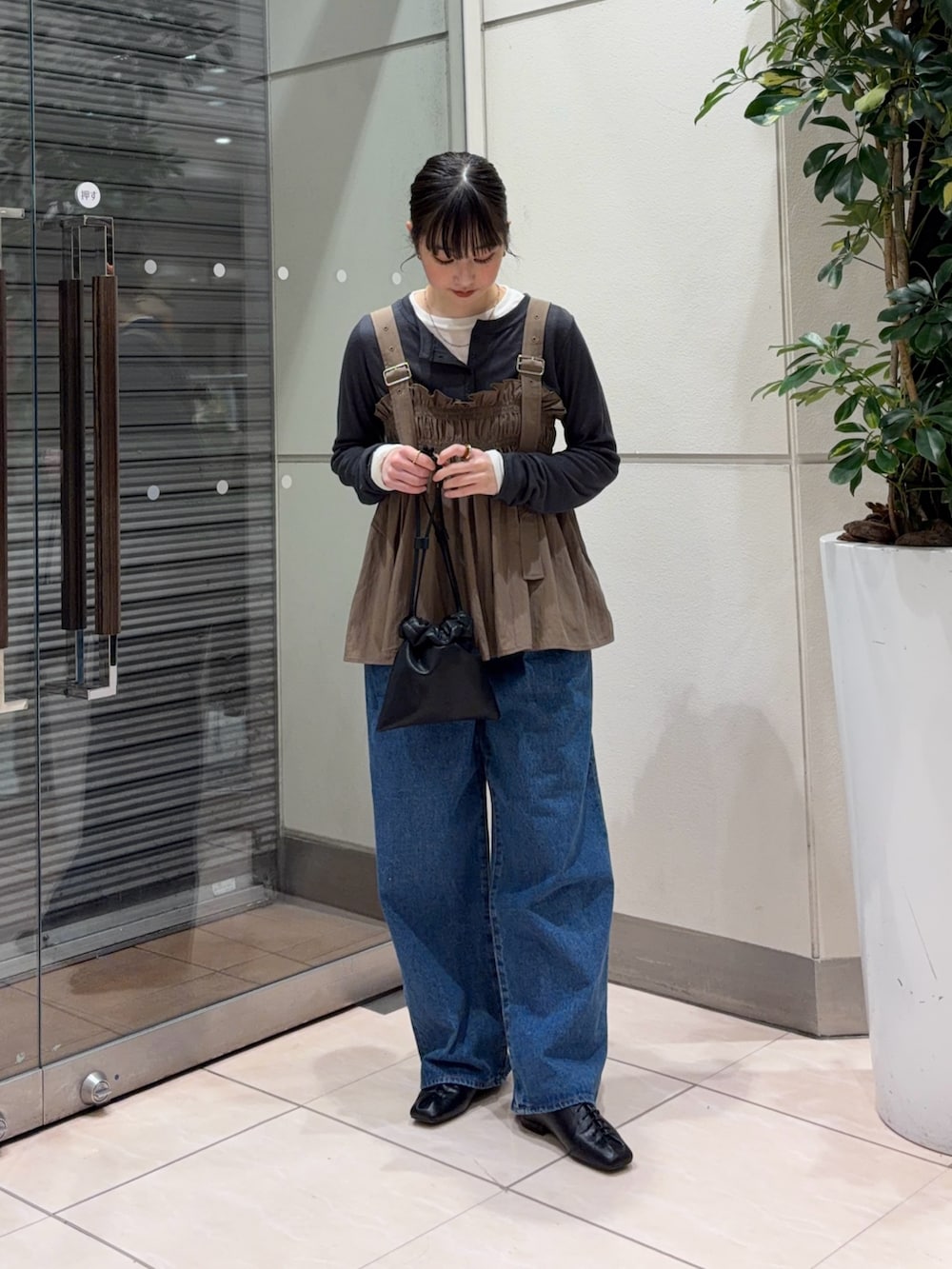 ブルー系のデニムパンツ、ブラック系のその他シューズ、ブラック系のショルダーバッグを着用したレディースの春コーディネートの2枚目の写真