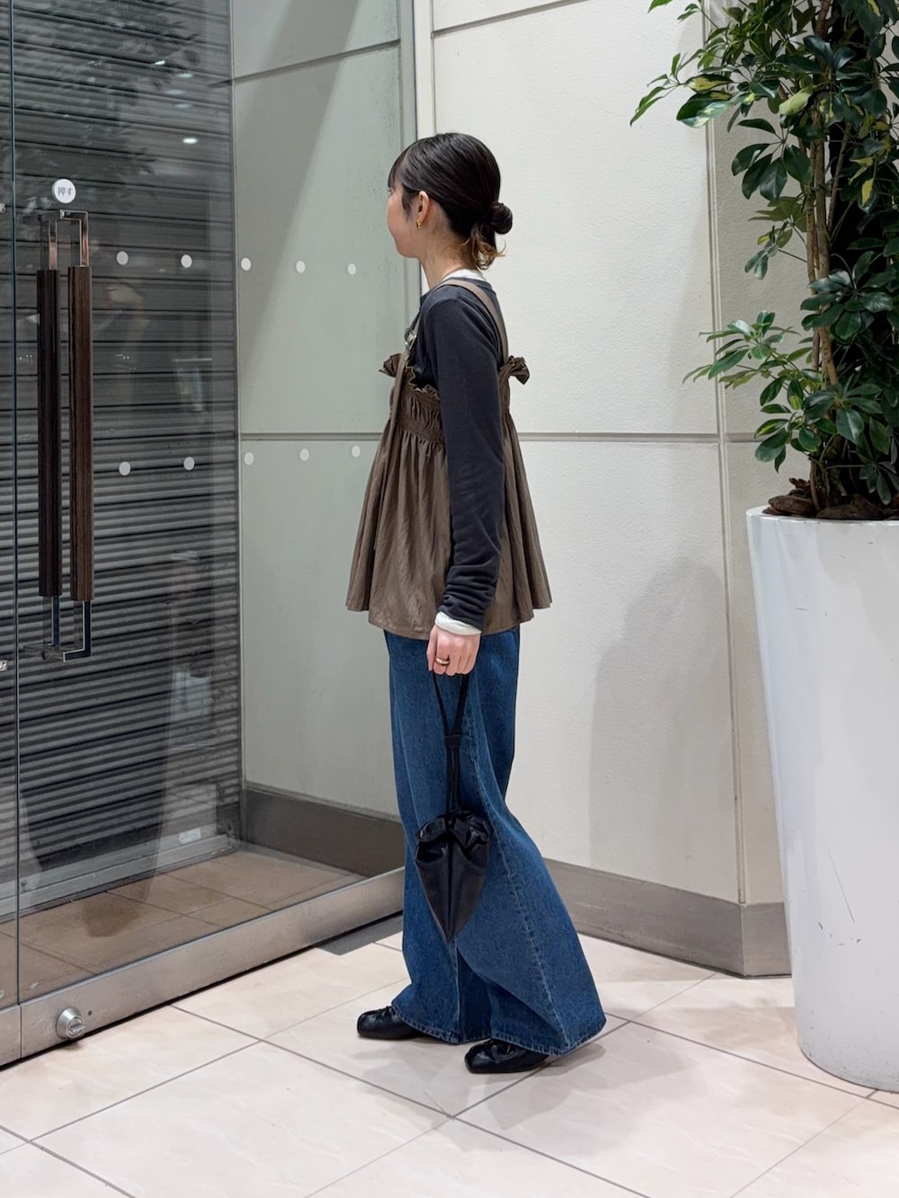 ブルー系のデニムパンツ、ブラック系のその他シューズ、ブラック系のショルダーバッグを着用したレディースの春コーディネートの3枚目の写真