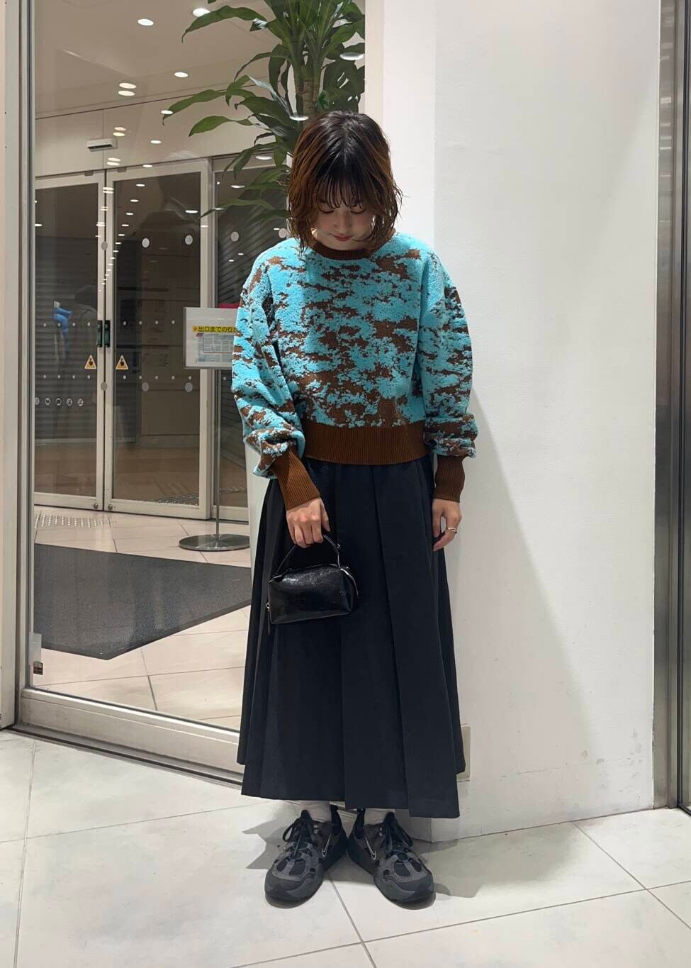 ブラウン系のニット/セーター、グレー系のワンピース、ブラック系のハンドバッグを着用したレディースの秋コーディネートの2枚目の写真