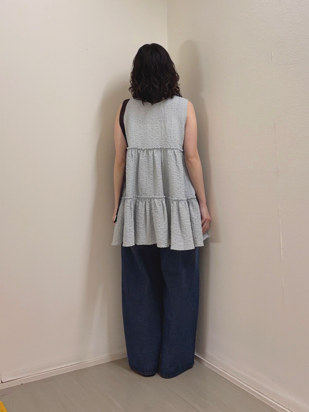 ブルー系のチュニック、ブルー系のデニムパンツ、ブラウン系のサンダルを着用したレディースの春コーディネートの3枚目の写真