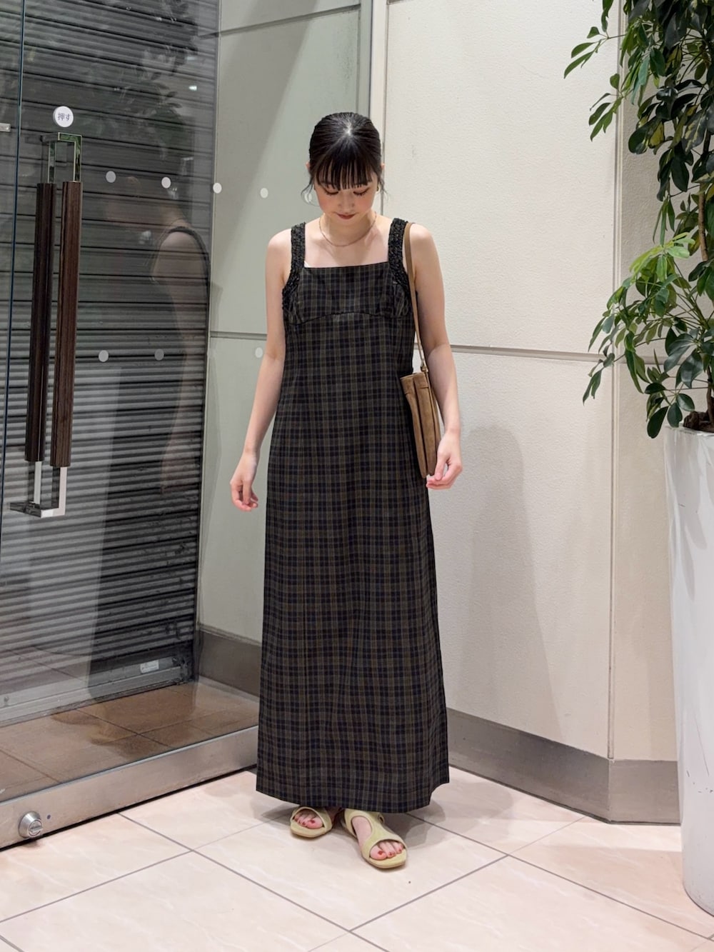 イエロー系のサンダル、イエロー系のショルダーバッグ、ブラック系のワンピースを着用したレディースの夏コーディネートの3枚目の写真