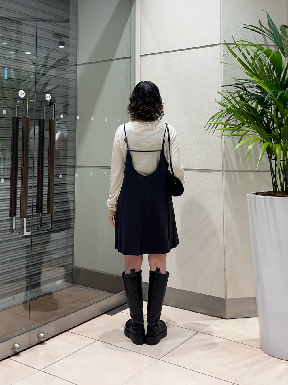 ブラック系のブーツ、グレー系のワンピース、ブラック系のショルダーバッグを着用したレディースの秋コーディネートの4枚目の写真