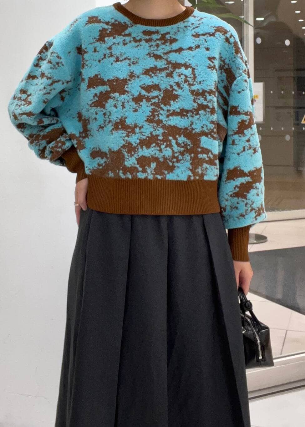 ブラウン系のニット/セーター、グレー系のワンピース、ブラック系のハンドバッグを着用したレディースの秋コーディネートの4枚目の写真