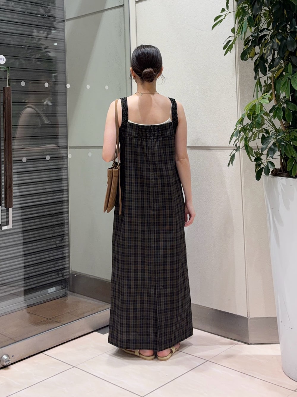 イエロー系のサンダル、イエロー系のショルダーバッグ、ブラック系のワンピースを着用したレディースの夏コーディネートの5枚目の写真