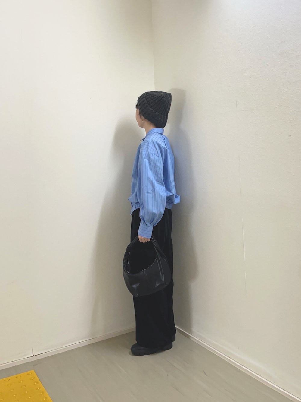 ブラック系のハンドバッグ、ブラウン系のブーツ、グレー系のシャツ/ブラウスを着用したレディースの冬コーディネートの3枚目の写真