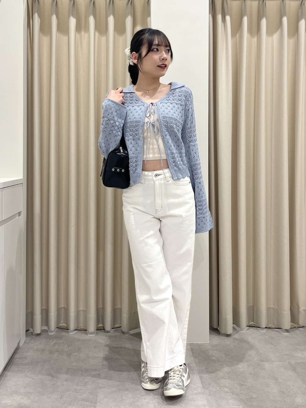 ブルー系のニット/セーター、ホワイト系のデニムパンツを着用したレディースの春コーディネートの2枚目の写真